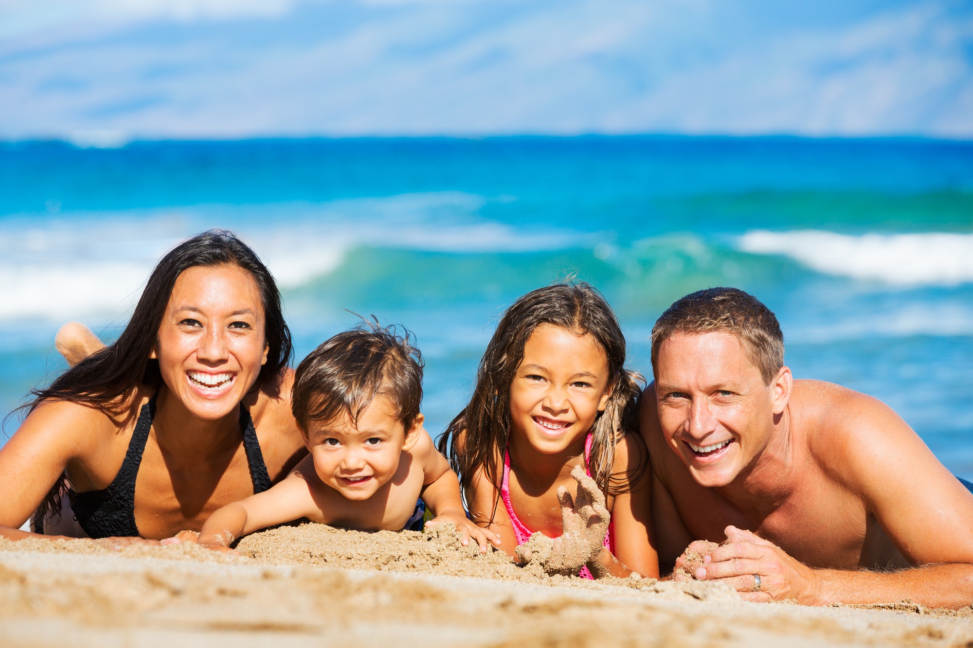 Young happy family having fun at the beach outdoors